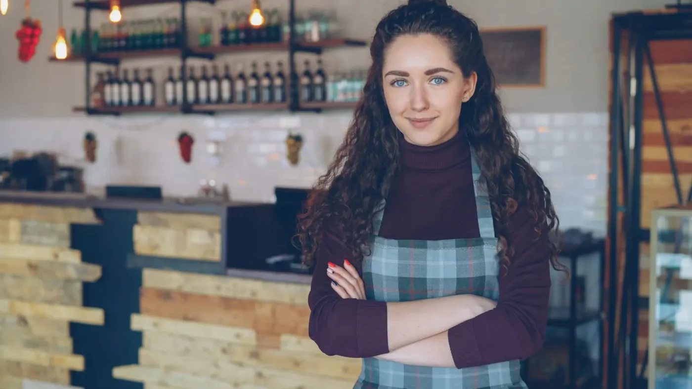 Cafe owner standing with arms crossed inside her shop