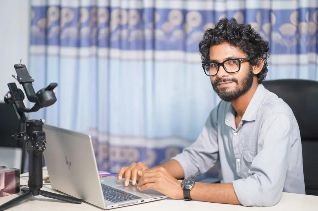 Web designer smiling at his laptop in a studio
