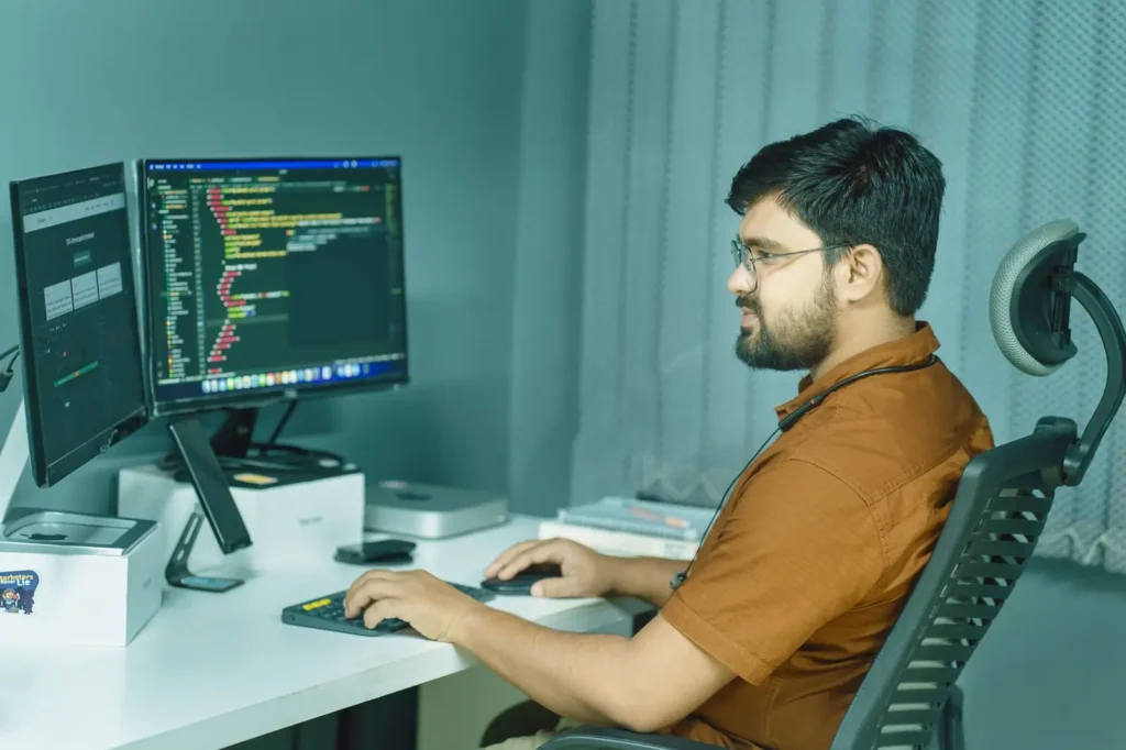 Developer writing code across two monitors