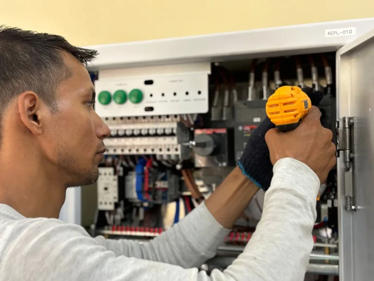 Electrician using a drill on an electrical panel
