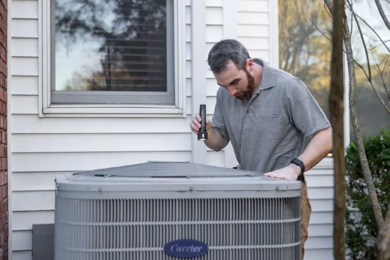 HVAC technician working on an outdoor air conditioning unit beside a home