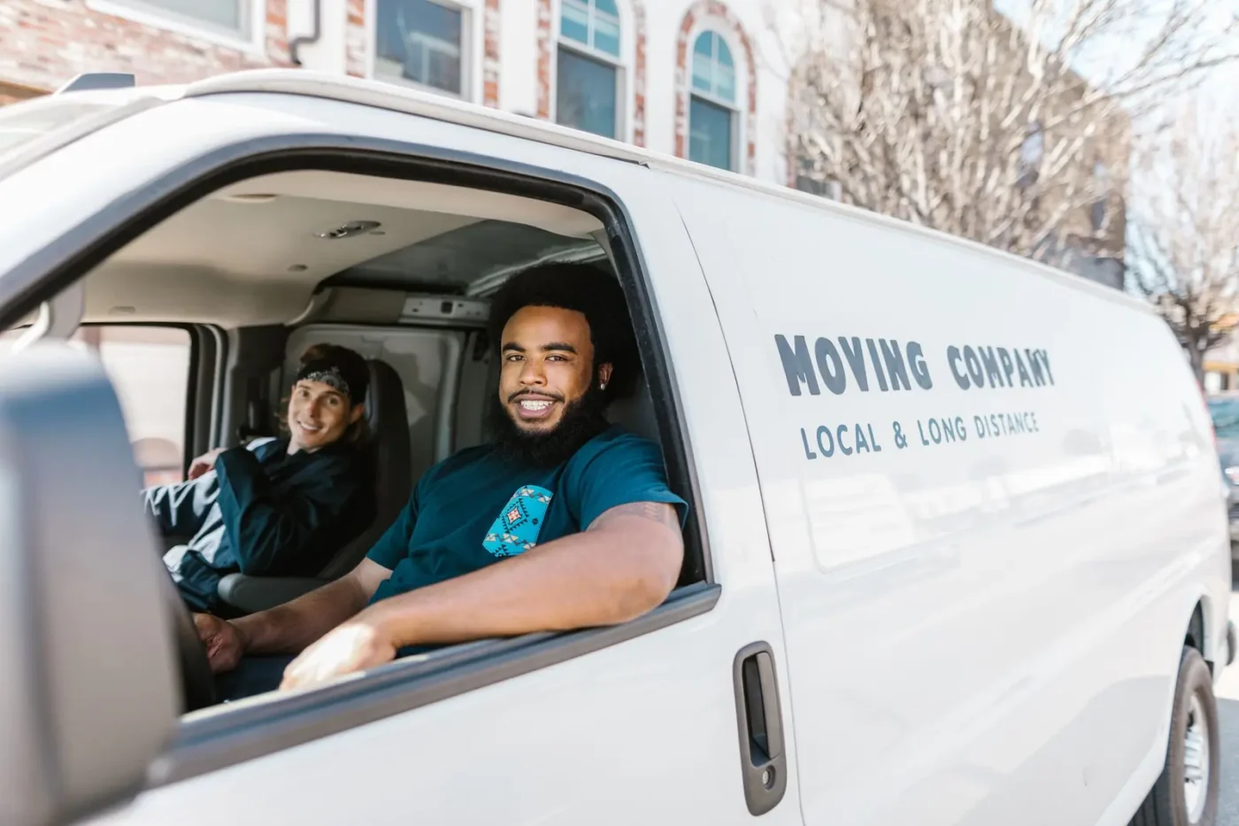 Two movers smiling from a moving company van