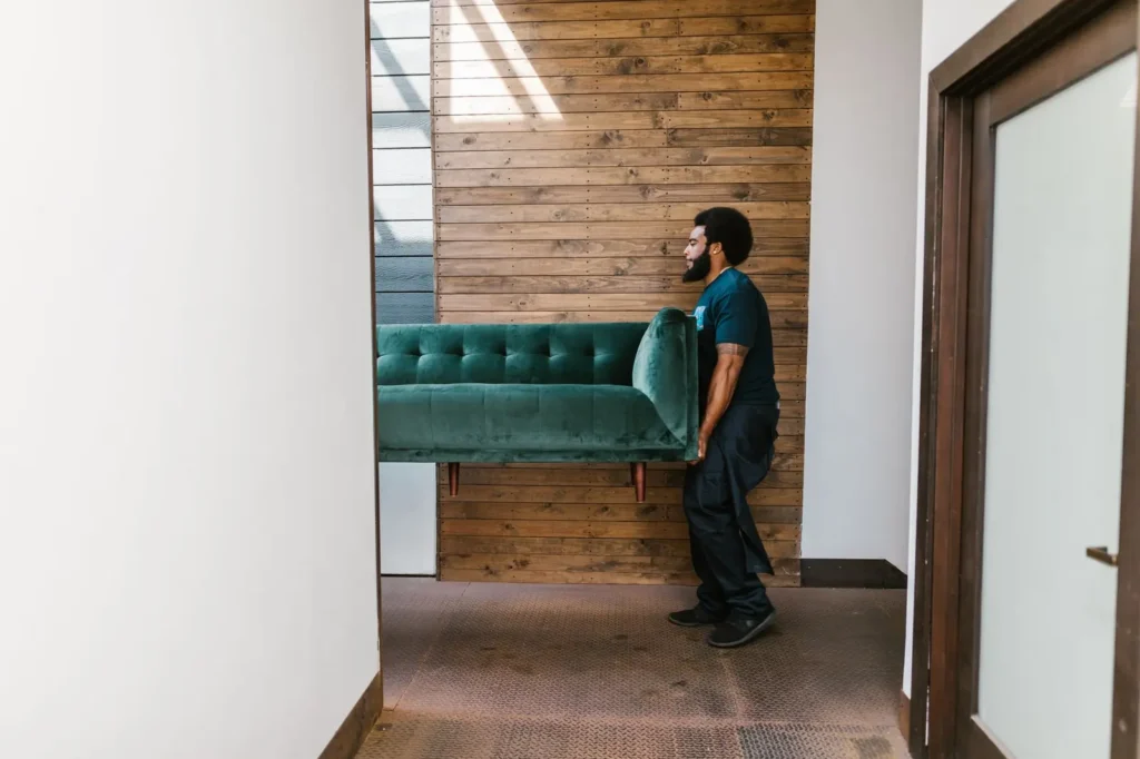 Mover carrying a sofa through a doorway