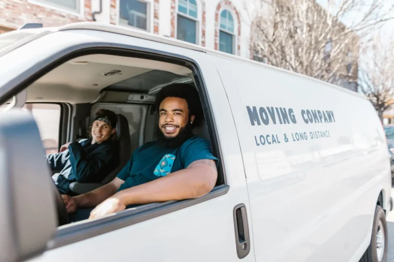 Two movers smiling from a moving company van