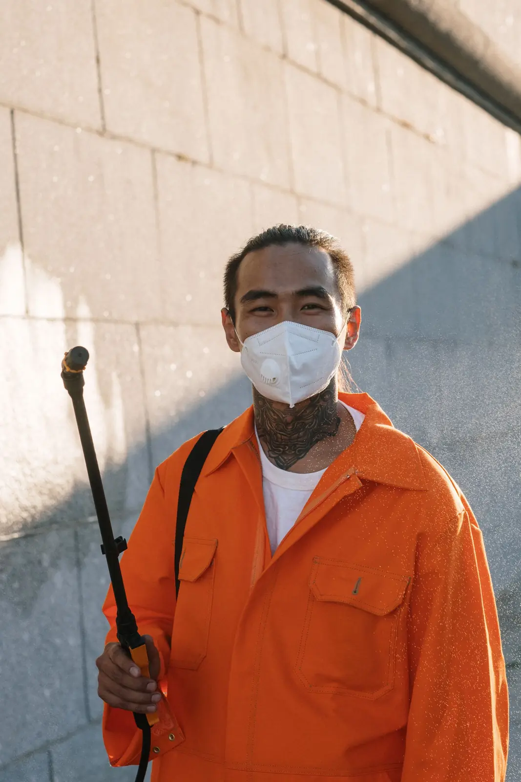 Pest control technician in coveralls holding a sprayer