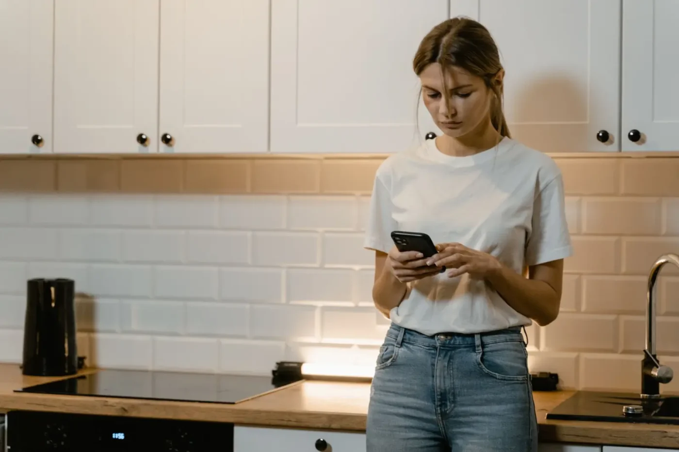 Woman searching on her phone in her kitchen