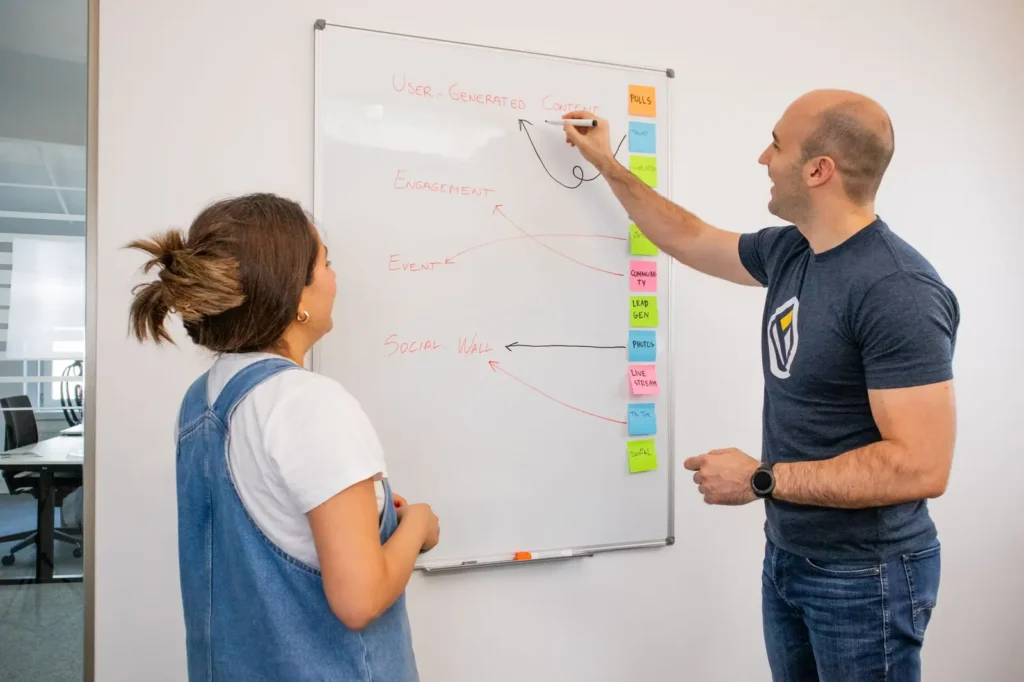 Two strategists mapping a plan on a whiteboard