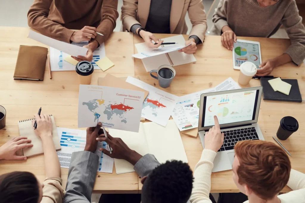 Overhead view of a team planning with charts, notes and laptops