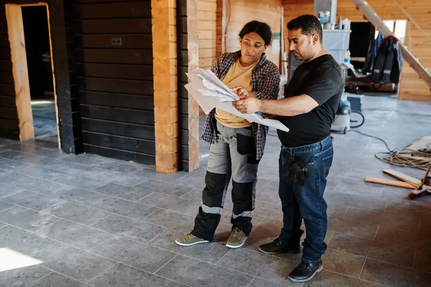 Contractors reviewing plans inside a home under renovation