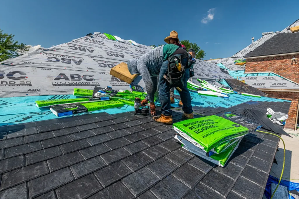 Roofers installing underlayment and shingles on a house