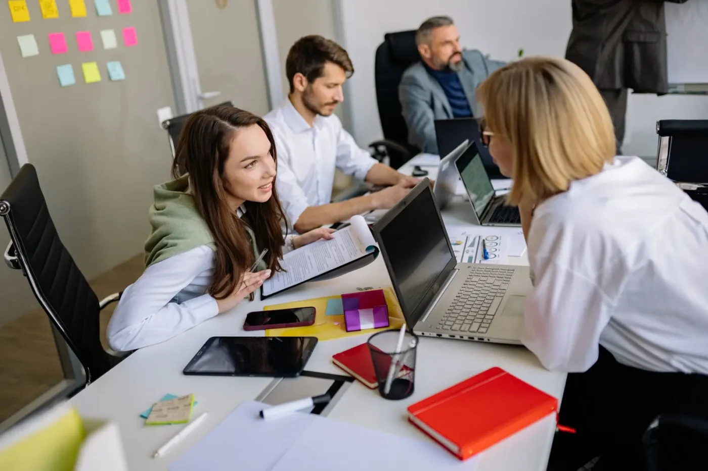 Team members comparing notes on laptops at a shared desk