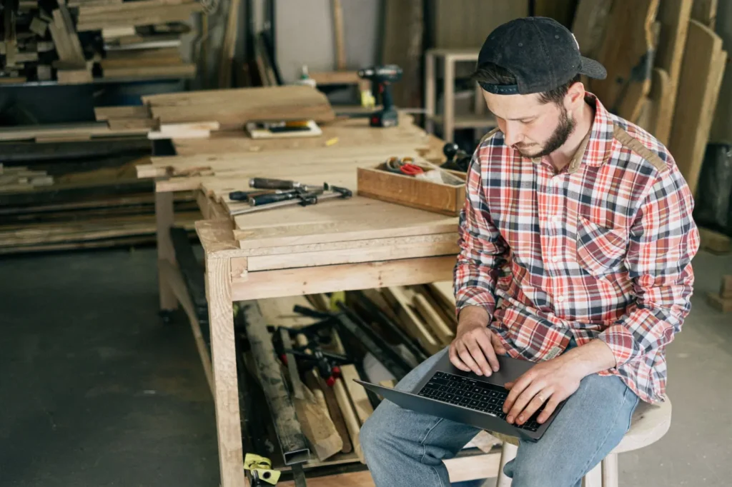 Tradesman in his workshop checking his laptop