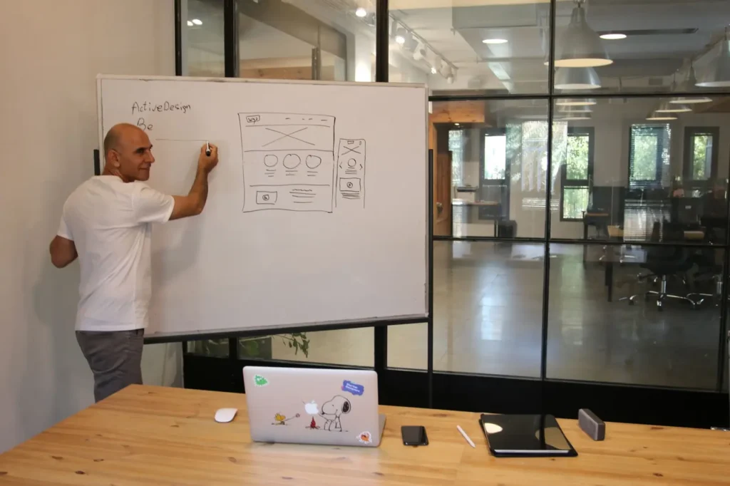 Strategist sketching a website wireframe on a whiteboard